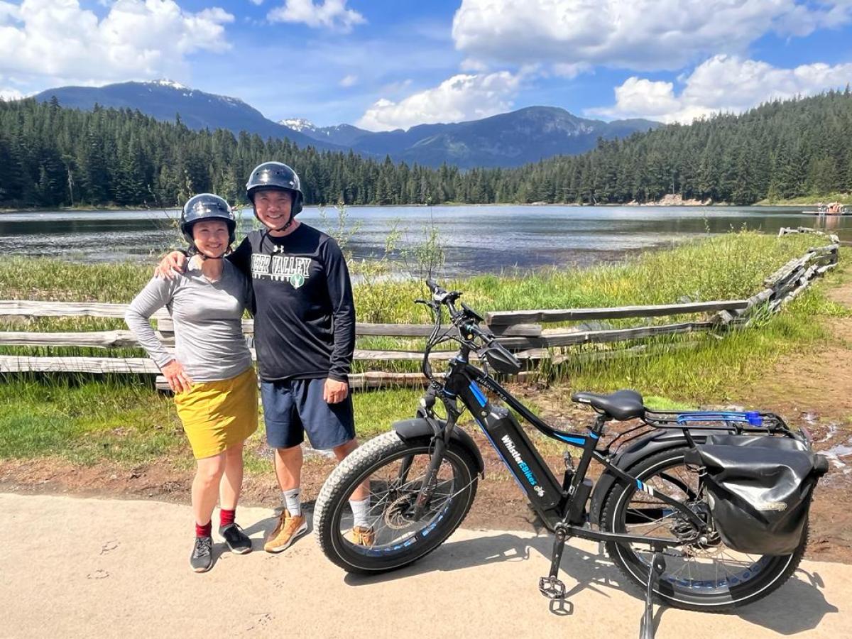 a group of people standing around a motorcycle in front of a mountain