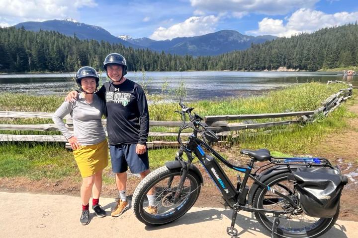 a group of people standing around a motorcycle in front of a mountain