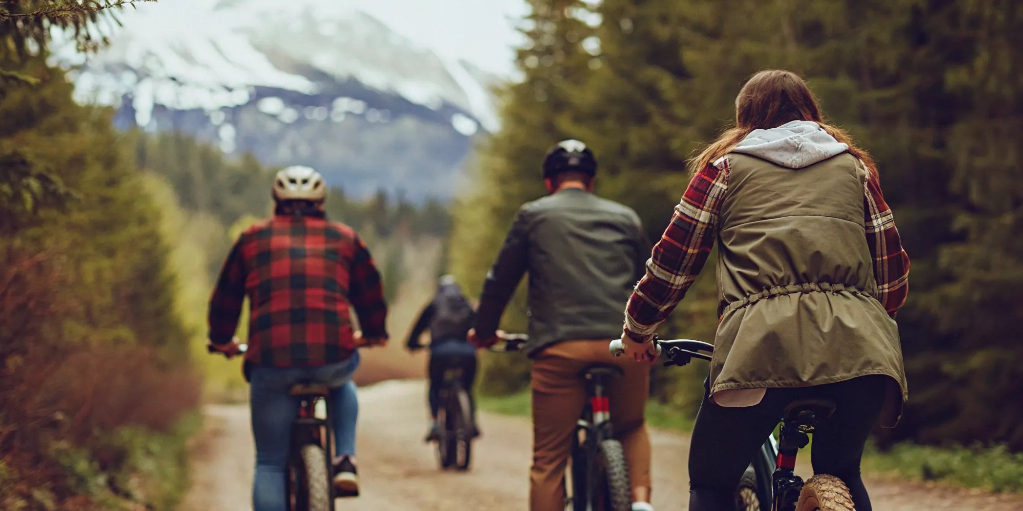 Group of cyclists riding fat tire eBikes on a scenic Whistler valley trail with glacier-fed lakes and mountains
