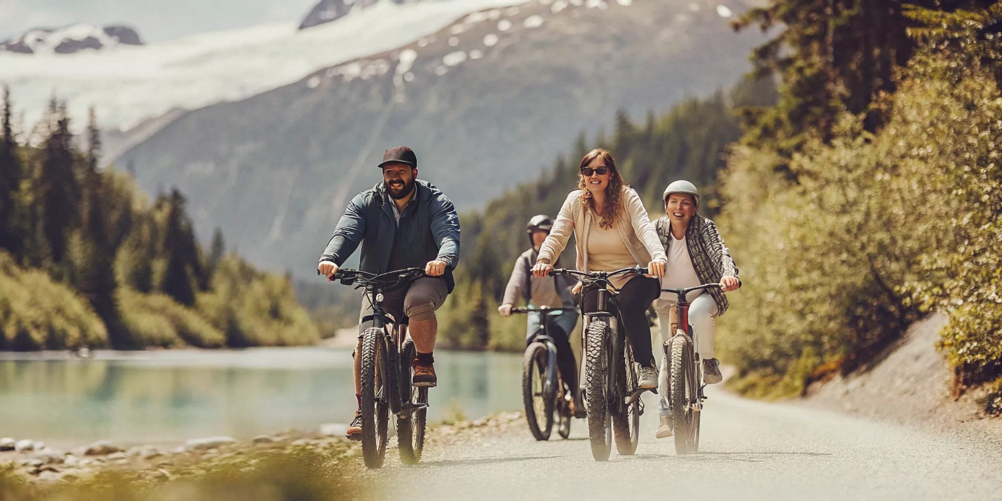 Family riding fat tire electric bikes on a scenic Whistler valley trail with mountain backdrop