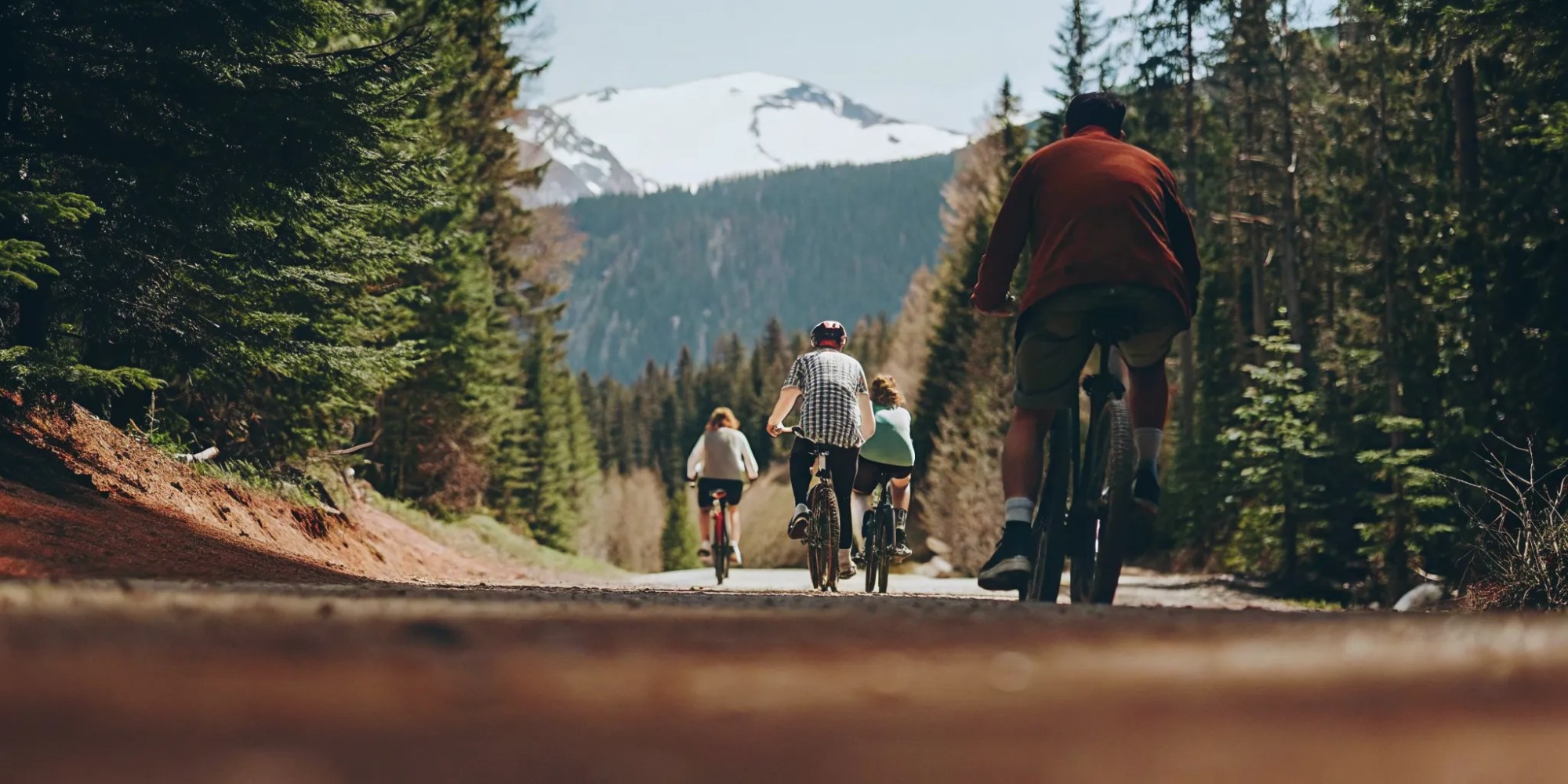Group riding fat tire eBikes on a scenic Whistler valley trail with mountains and lakes in the background