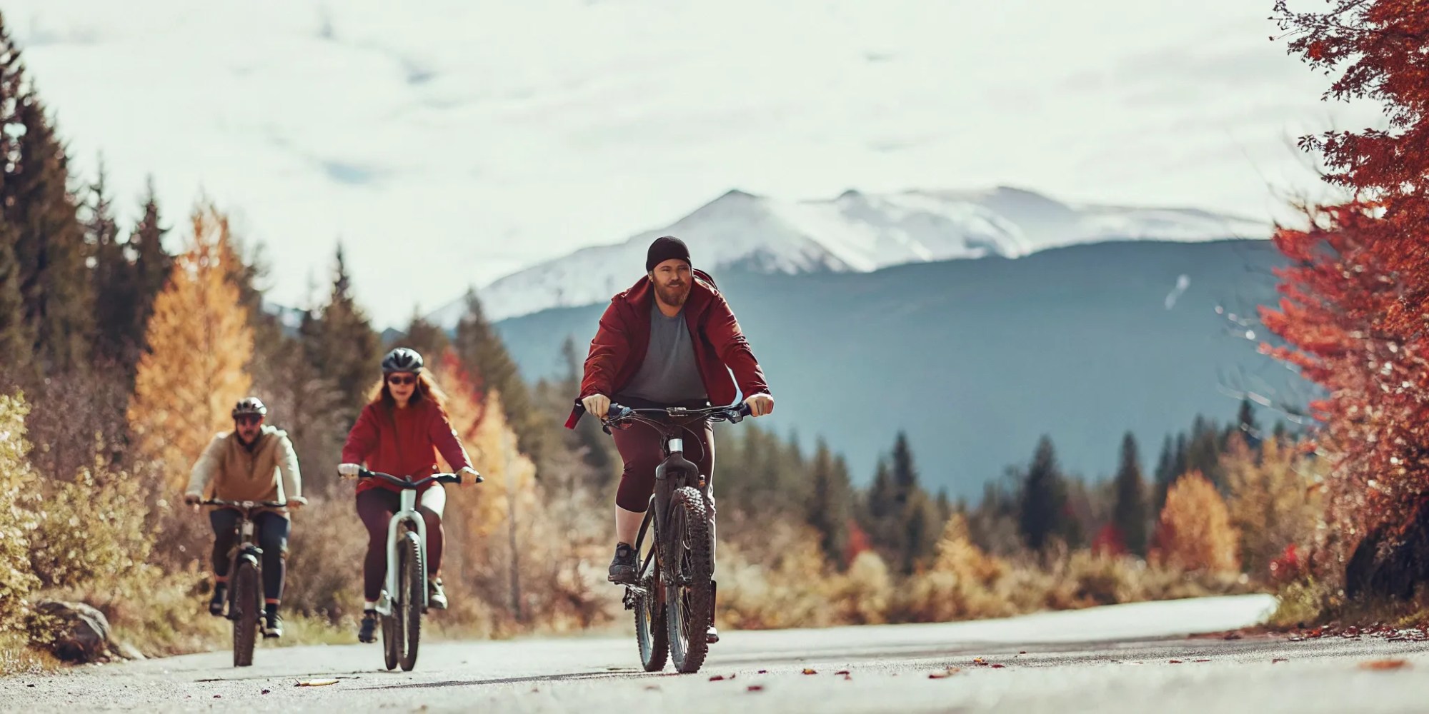 Group of cyclists riding fat tire eBikes on a scenic Whistler valley trail in autumn with golden foliage and mountain views